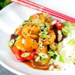 Sweet and sour prawns stir-fry served with rice, spring onions and sesame seeds.