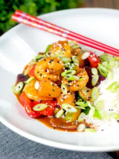 Sweet and sour prawns stir-fry served with rice, spring onions and sesame seeds.