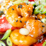 Close-up sweet and sour prawns stir-fry served with spring onions and sesame seeds featuring a title overlay.