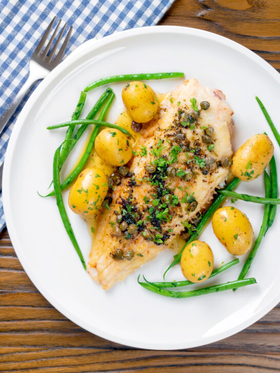 Overhead whole pan-fried lemon sole meuniere with a caper and butter sauce.