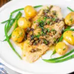 Whole pan-fried lemon sole meuniere with a caper and butter sauce featuring a title overlay.