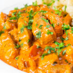 Close-up pork paprikash with a fresh parsley garnish.