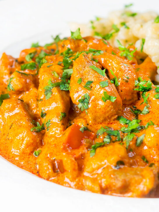 Close-up pork paprikash with a fresh parsley garnish.