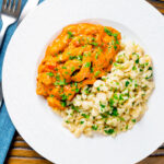 Overhead Hungarian pork paprikash served with homemade nokedli featuring a title overlay.