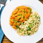 Overhead Hungarian pork paprikash served with homemade nokedli featuring a title overlay.