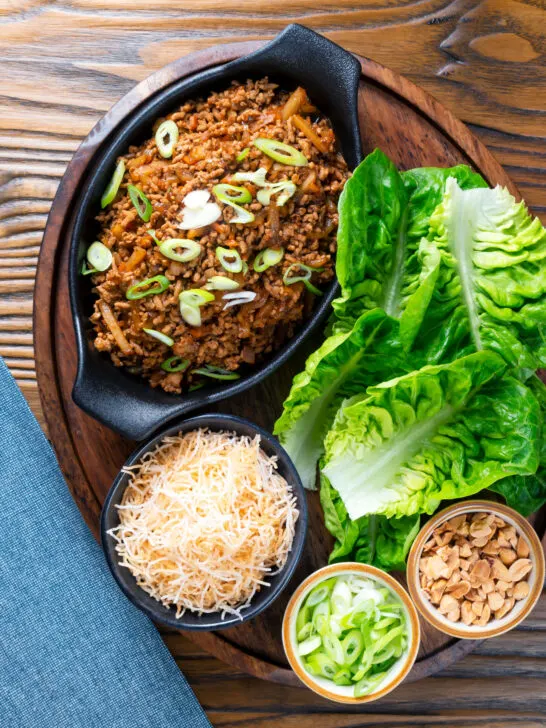 Overhead Chinese takeaway minced pork yuk sung with lettuce cups fried noodles and peanuts.