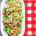 Overhead spicy cucumber salad with tomato, chilli and toasted peanuts.