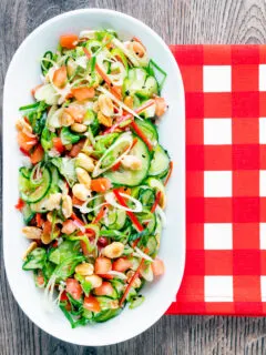 Overhead spicy cucumber salad with tomato, chilli and toasted peanuts.