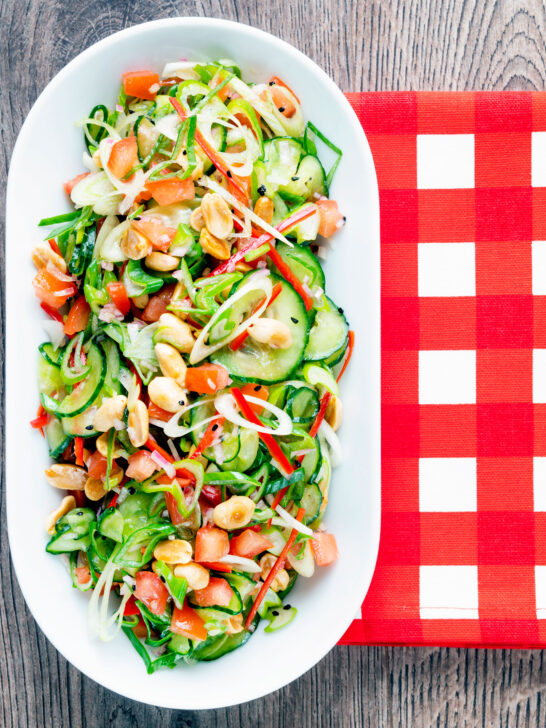 Overhead spicy cucumber salad with tomato, chilli and toasted peanuts.
