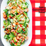 Overhead spicy cucumber salad with tomato, chilli and toasted peanuts featuring a title overlay.