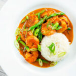 Overhead Thai red prawn curry with green beans served with rice.