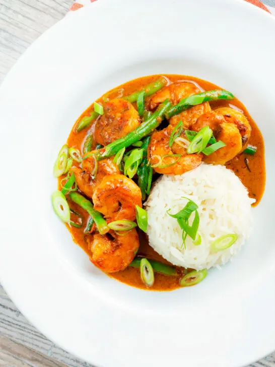 Overhead Thai red prawn curry with green beans served with rice.