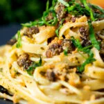 Close-up tuna pesto fettuccini with crispy capers, golden breadcrumbs and fresh basil.