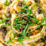 Overhead close-up tuna pesto fettuccini with crispy capers, golden breadcrumbs and fresh basil.