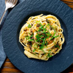 Overhead tuna pesto pasta with crispy capers, golden breadcrumbs and fresh basil.
