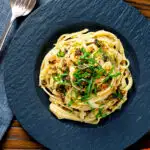 Overhead tuna pesto pasta with crispy capers, golden breadcrumbs and fresh basil.