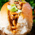 Close-up Japanese yakisoba pan stir-fried udon noodles served in a hot dog bun featuring a title overlay.