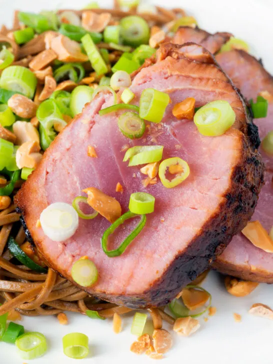 Close-up baked tuna steak with a honey and soy glaze served with noodle salad.