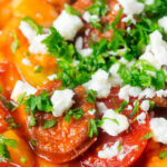 Close-up Spanish chorizo and butterbean stew with crumbled feta cheese and parsley.