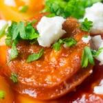 Close-up chorizo and butter bean stew with crumbled feta cheese and parsley.