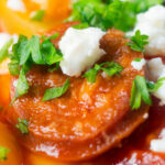 Close-up chorizo and butter bean stew with crumbled feta cheese and parsley featuring a title overlay.