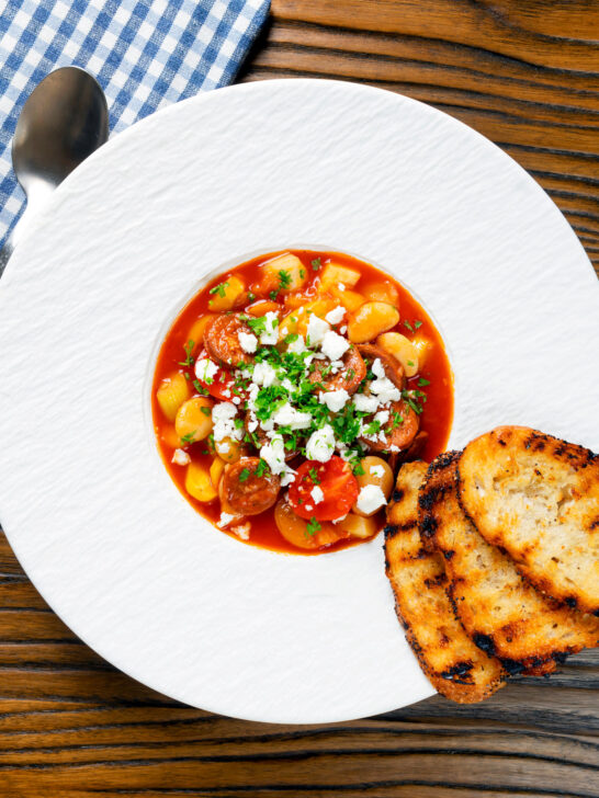 Overhead Spanish chorizo and butterbean stew with crumbled feta cheese and parsley.