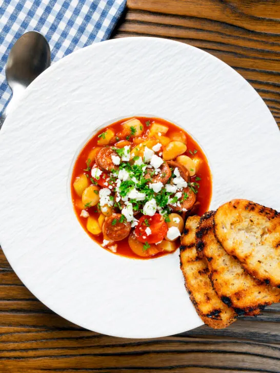 Overhead Spanish chorizo and butterbean stew with crumbled feta cheese and parsley.