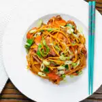 Overhead hoisin duck chow mein stir fry with noodles, carrots and runner beans.