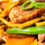 Close-up hoisin duck chow mein stir fry with noodles, carrots and runner beans.