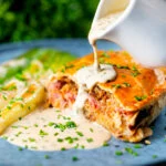 Individual ham, potato and apple fidget pie, cut open to show filling with a cider cream sauce.