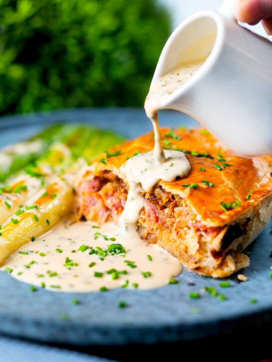 Individual ham, potato and apple fidget pie, cut open to show filling with a cider cream sauce.