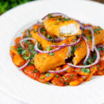 Close-up Indian-inspired fish finger and butter bean curry featuring a title overlay.
