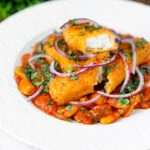 Close-up Indian-inspired fish finger and butter bean curry featuring a title overlay.