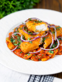 Close-up Indian-inspired fish finger and butter bean curry featuring a title overlay.