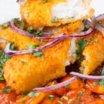 Close-up fish finger and butter bean curry served with red onion and coriander featuring a title overlay.