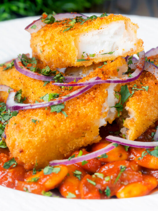 Close-up fish finger and butter bean curry served with red onion and coriander featuring a title overlay.