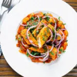 Overhead fish finger and butter bean curry served with red onion and coriander.