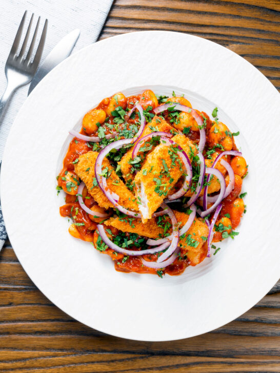 Overhead fish finger and butter bean curry served with red onion and coriander.