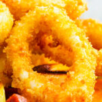 Close-up fried calamari rings with romesco sauce, leeks, chorizo and capers.