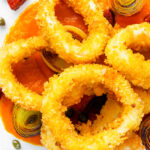 Overhead fried and breaded calamari rings with romesco sauce, leeks, chorizo and capers.