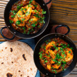 Overhead king prawn or shrimp bhuna served with chapatis and fresh coriander.