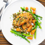 Overhead lemon and caper chicken piccata served with asparagus and carrots featuring a title overlay.