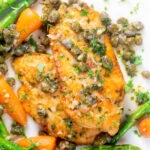 Overhead close-up lemon and caper chicken piccata served with asparagus and carrots.