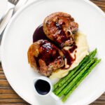 Overhead minted lamb chops with red wine sauce, mashed potato and asparagus.