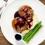 Overhead minted lamb chops with red wine sauce, mashed potato and asparagus.
