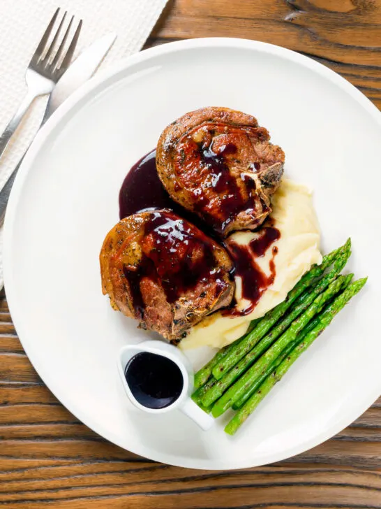 Overhead minted lamb chops with red wine sauce, mashed potato and asparagus.