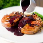 Rich red wine sauce being poured over pan-fried minted lamb chops.