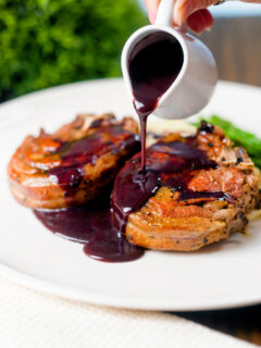 Rich red wine sauce being poured over pan-fried minted lamb chops.