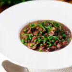 Mushroom pearl barley risotto or orzotto cooked with red wine and peas.