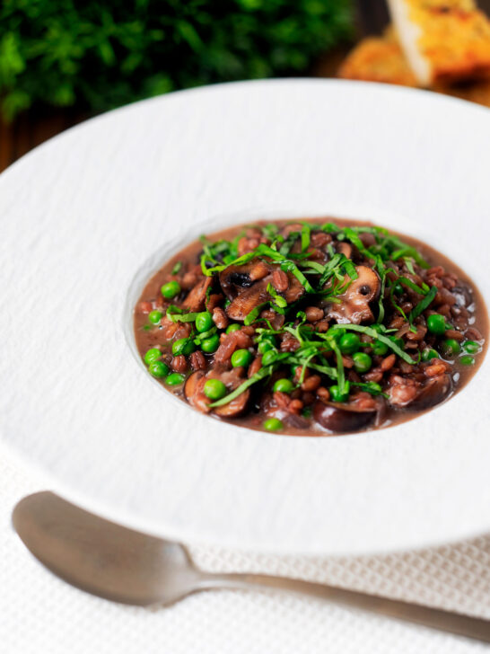 Mushroom pearl barley risotto or orzotto cooked with red wine and peas.